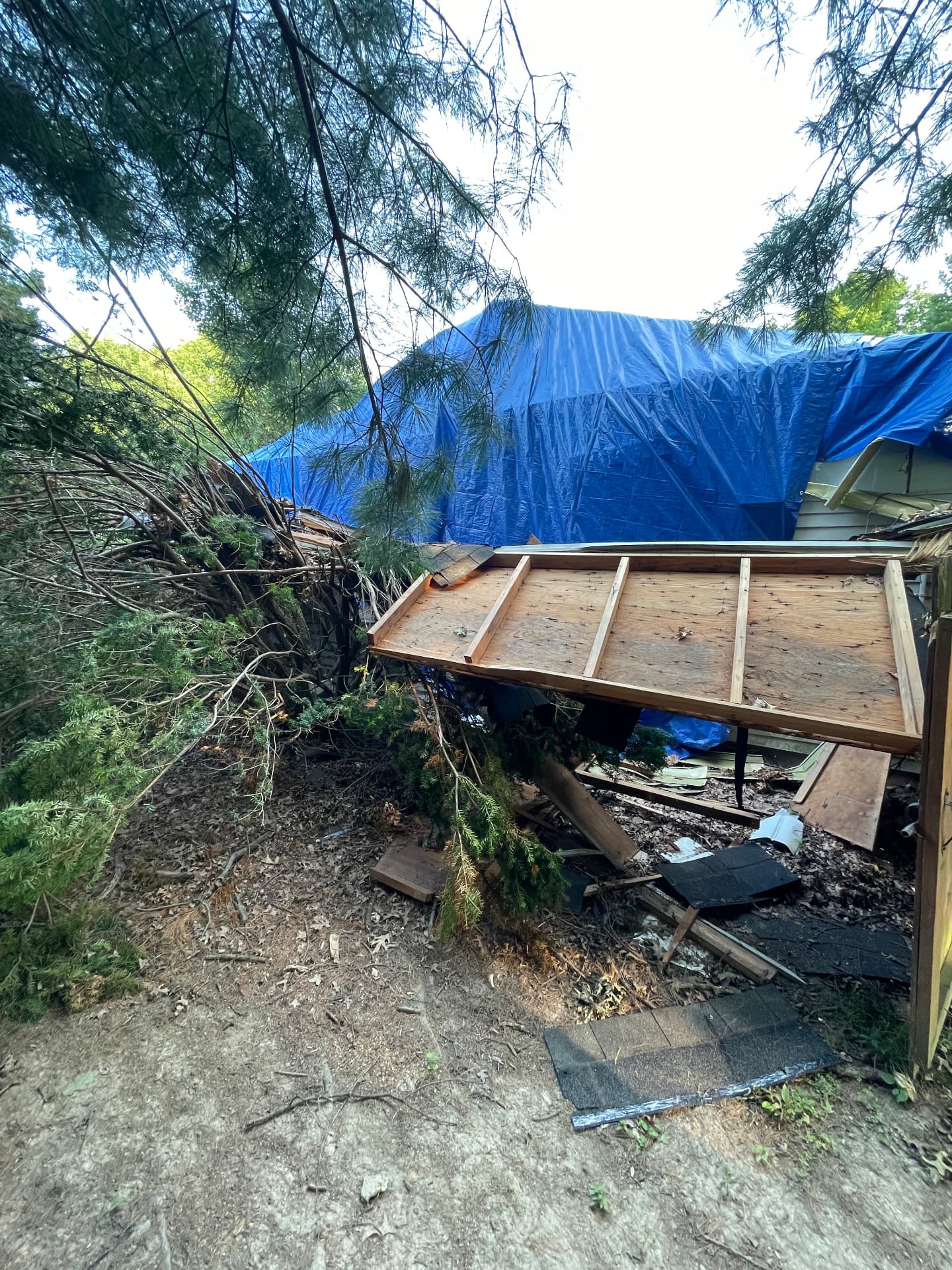 Storm-damaged shed, brush piles, and roof debris in a Northeast Ohio backyard before cleanup